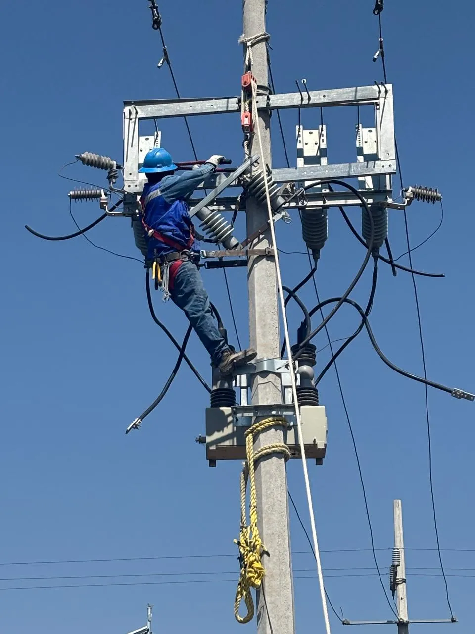 Técnico instalando equipo eléctrico de media tensión en poste